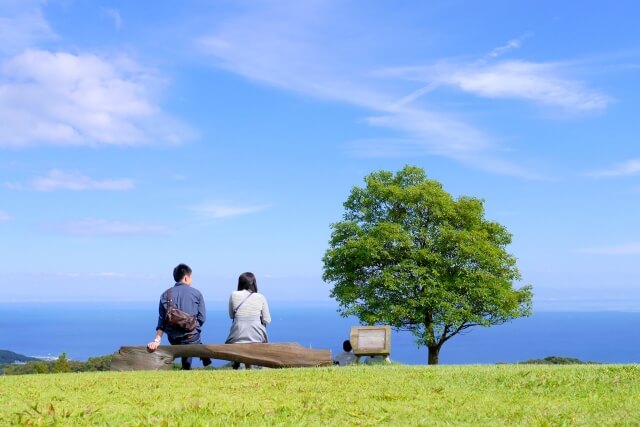 海の見えるところでピクニックデートをするカップル