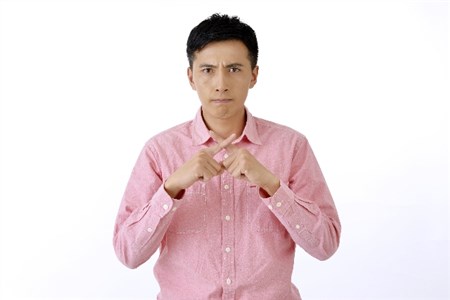 指でバツ印を作る男性