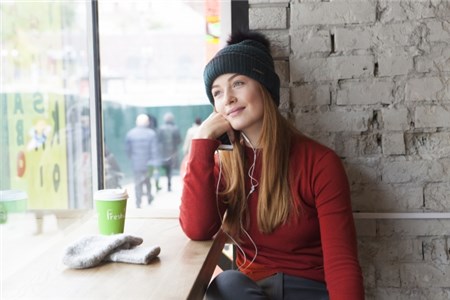 カフェの窓際で読書とコーヒーを楽しむ白人女性